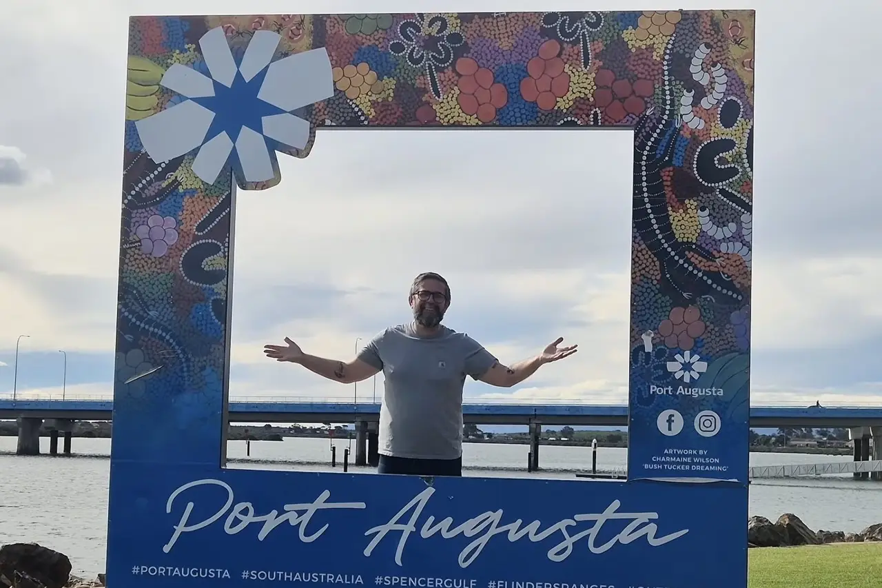 Mark in a photo frame at Port Augusta, with the bridge and gulf behind.